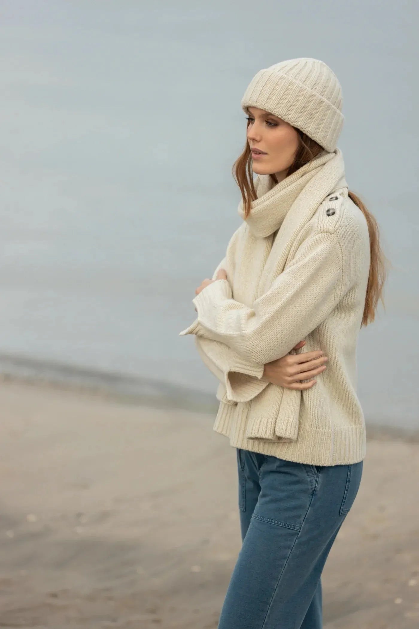 Wollpullover - 100% Wolle mit Knopfdetails, kombiniert mit Mütze und Schal, ideal für kalte Tage am Wasser, stilvoll und wärmend.