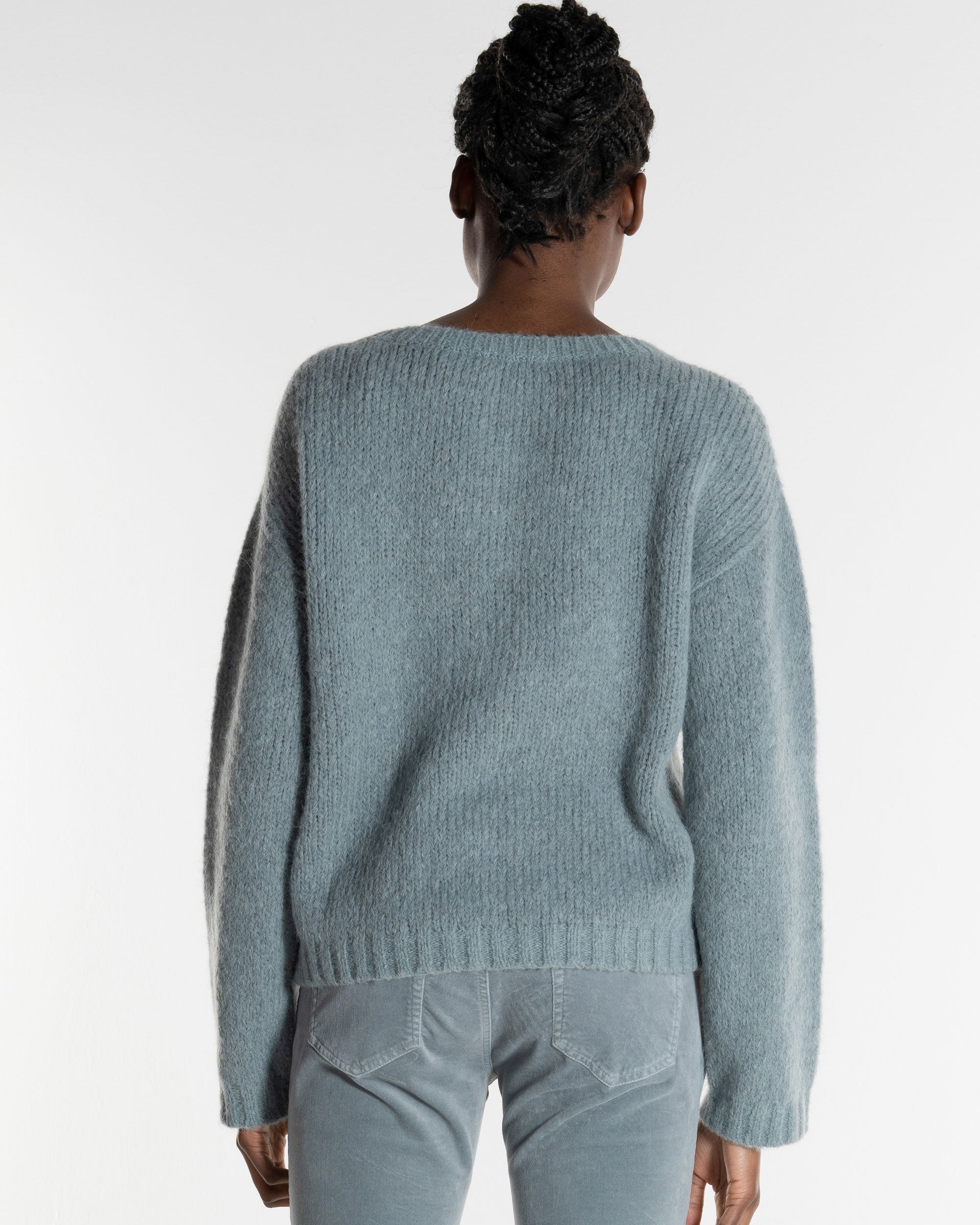 Frau mit grau blauem Strickpullover von hinten