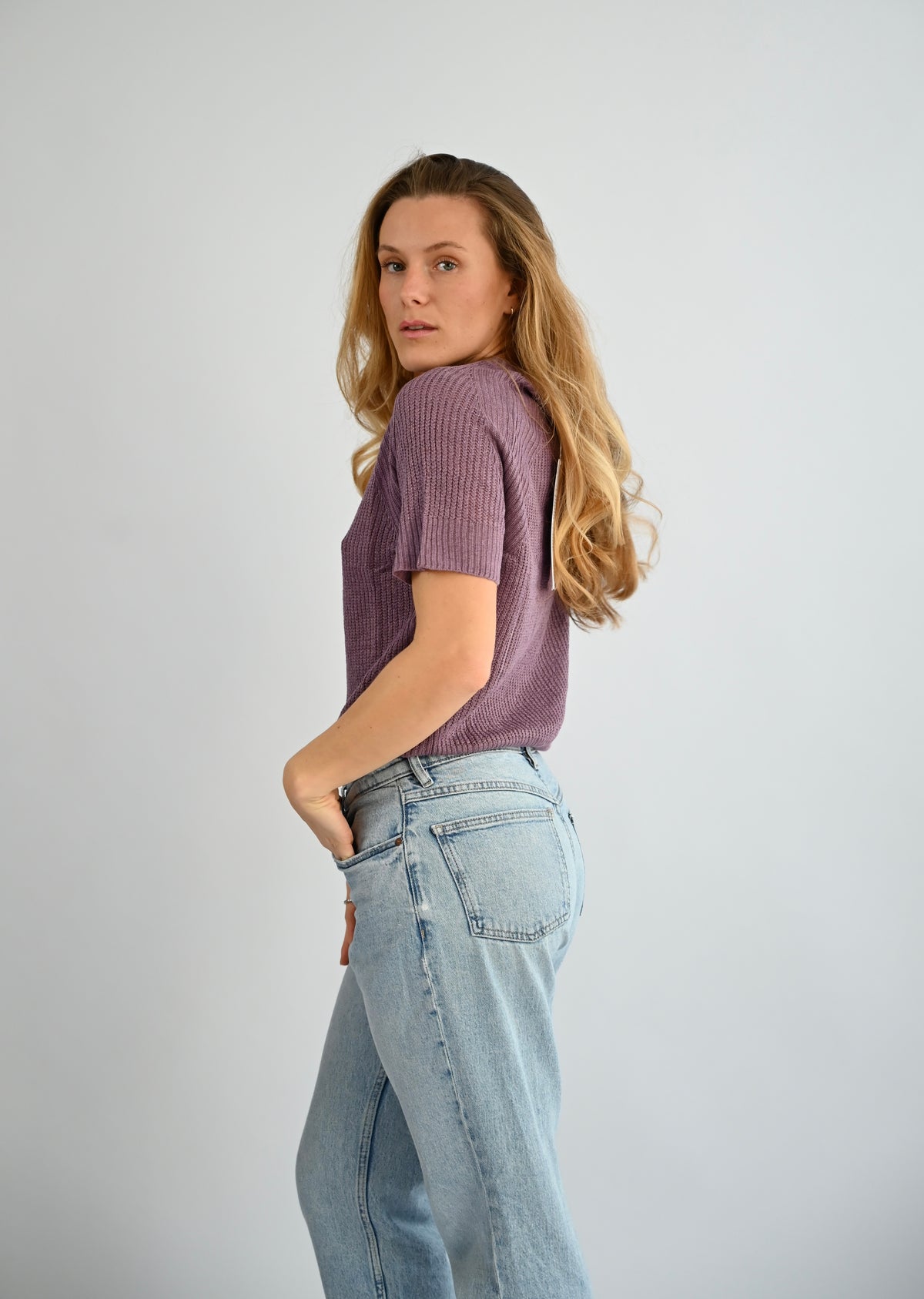 ELODIE Ribb Sweater in Lavendel, Seitenansicht am Model mit kurzem Arm und Rundhalsausschnitt, kombiniert mit heller Jeans #farbe_lavendel