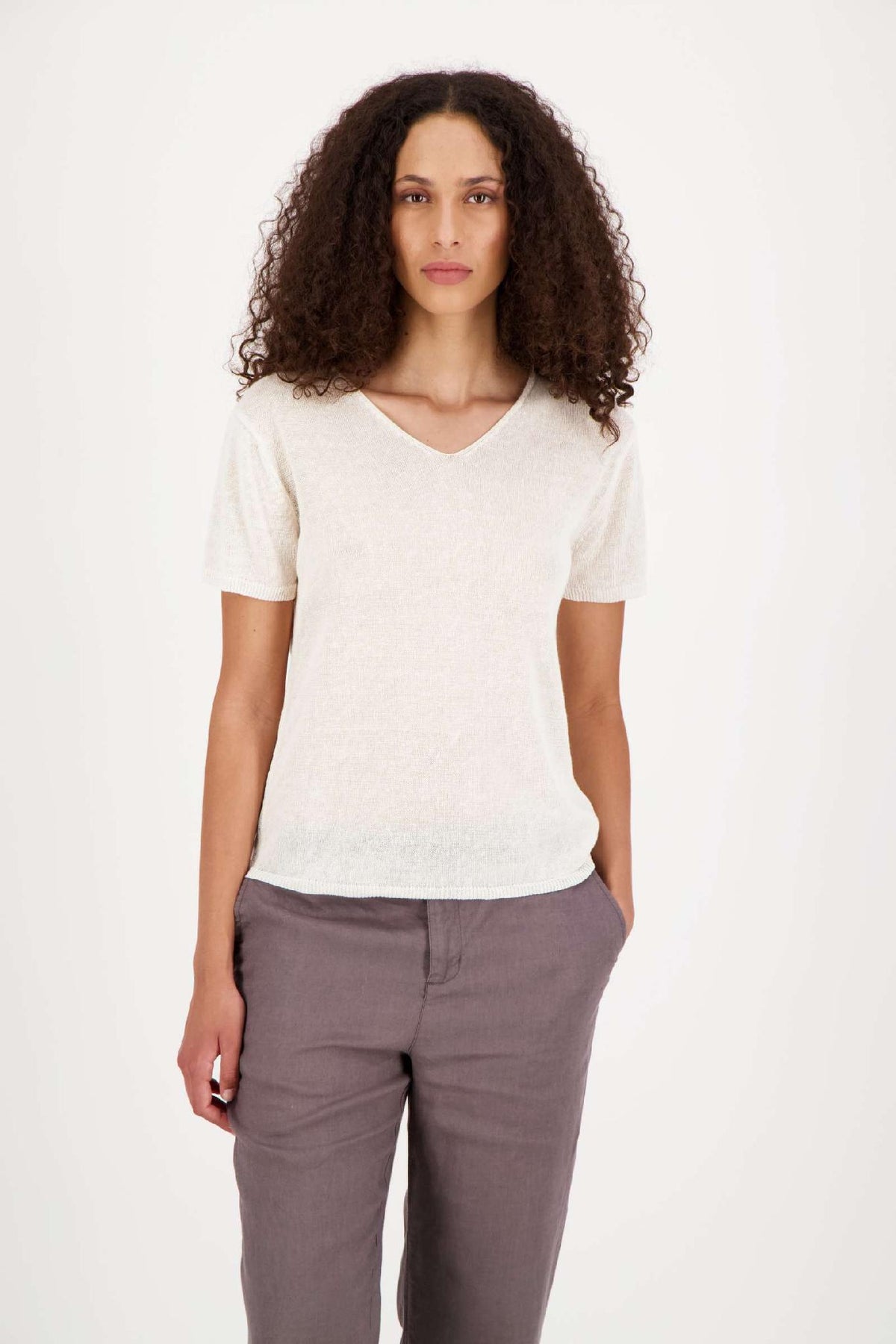 ELISA Kurzarm-Pullover in Weiß, Frontansicht am Model, V-Ausschnitt und kurze Ärmel, kombiniert mit grauer Hose #farbe_weiß